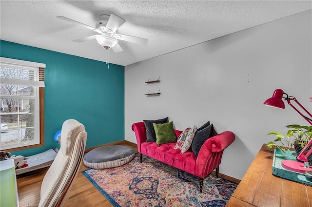 sitting room featuring a textured ceiling, wood finished floors, a ceiling fan, and baseboards