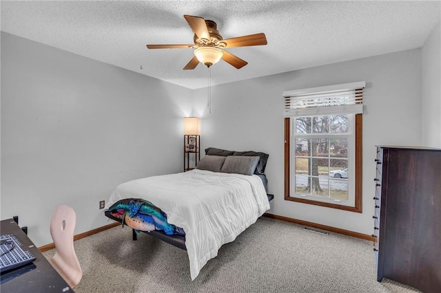 carpeted bedroom with a textured ceiling, ceiling fan, visible vents, and baseboards