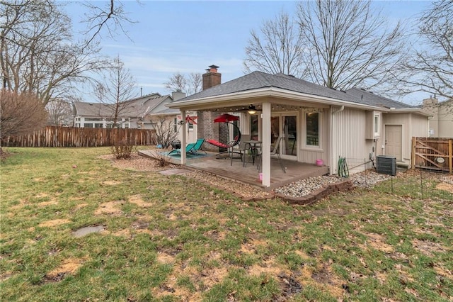 back of house featuring fence, a ceiling fan, a yard, a chimney, and a patio area