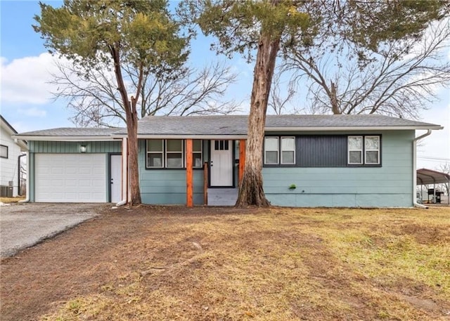 ranch-style house featuring a garage, central AC unit, and a front lawn