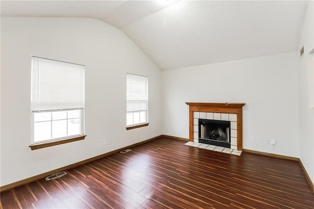 unfurnished living room featuring vaulted ceiling, a tile fireplace, and dark hardwood / wood-style floors