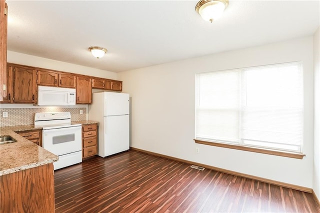 kitchen with backsplash, white appliances, dark wood-type flooring, and light stone countertops