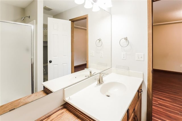 bathroom featuring an enclosed shower, vanity, and wood-type flooring