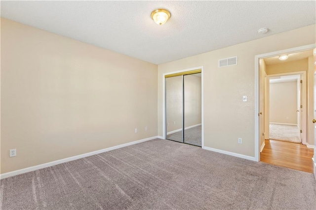 unfurnished bedroom with carpet floors, a closet, and a textured ceiling