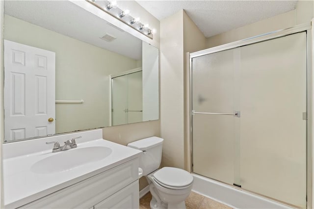 bathroom with vanity, toilet, a shower with door, and a textured ceiling