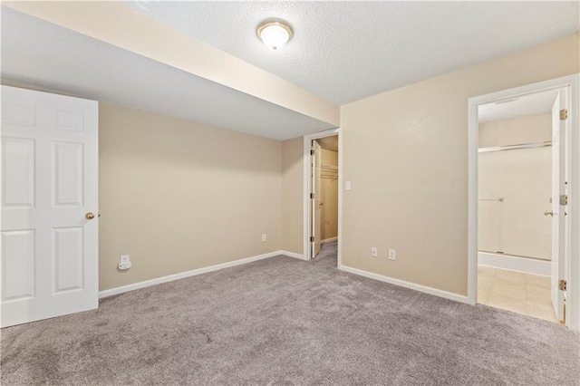 unfurnished bedroom with ensuite bathroom, light colored carpet, and a textured ceiling