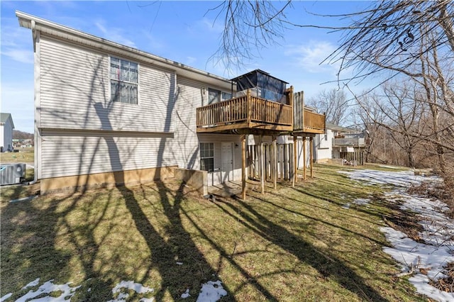 snow covered rear of property with central AC, a deck, and a lawn