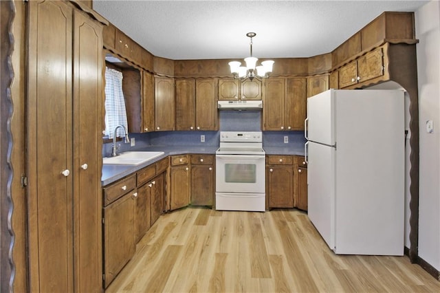 kitchen featuring pendant lighting, sink, white appliances, a notable chandelier, and light hardwood / wood-style floors