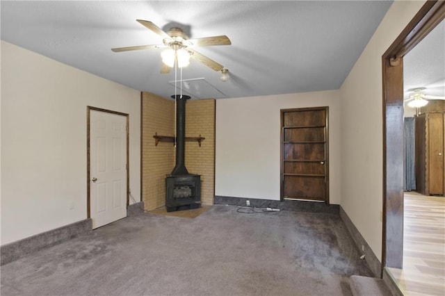 unfurnished living room with dark colored carpet, ceiling fan, and a wood stove