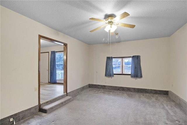 carpeted empty room featuring ceiling fan and a textured ceiling