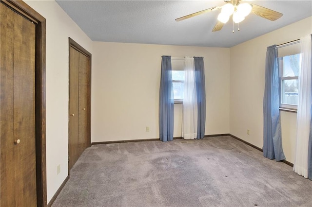 unfurnished bedroom with two closets, light colored carpet, and ceiling fan