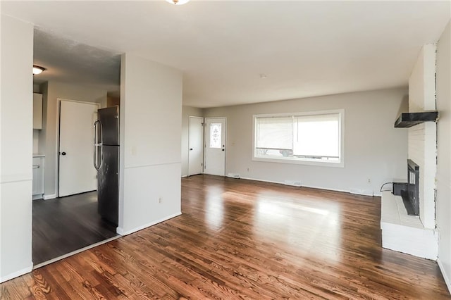 unfurnished living room featuring hardwood / wood-style floors and a brick fireplace