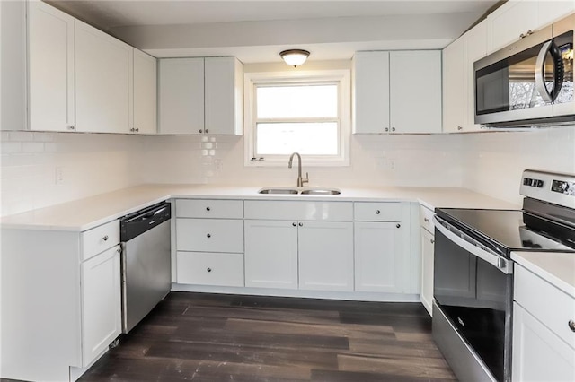 kitchen with appliances with stainless steel finishes, tasteful backsplash, white cabinetry, sink, and dark wood-type flooring