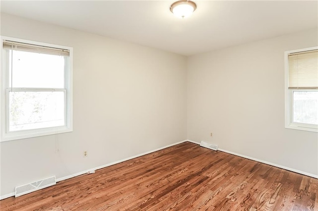 unfurnished room with wood-type flooring and a healthy amount of sunlight