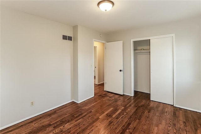 unfurnished bedroom with dark wood-type flooring and a closet