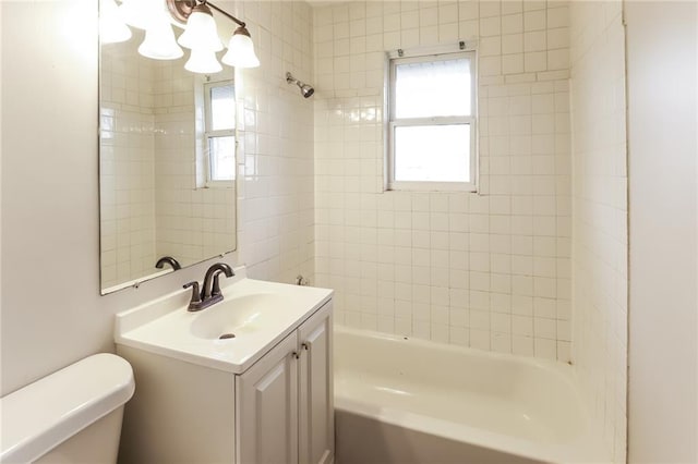 full bathroom featuring tiled shower / bath, vanity, and toilet