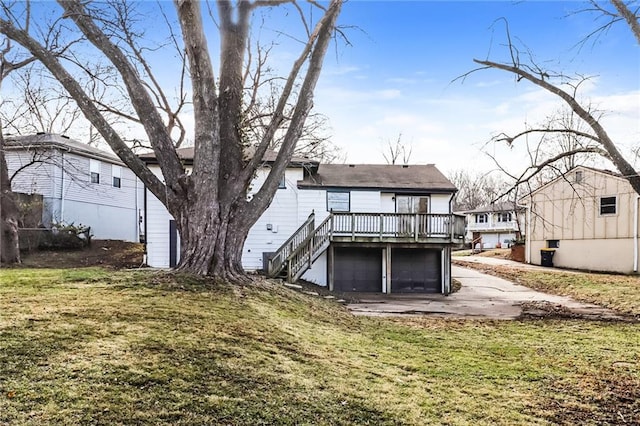 rear view of house with a garage, a yard, and a deck