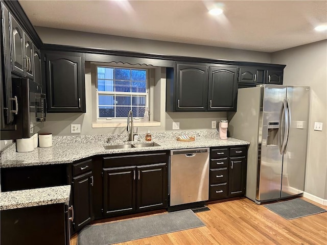 kitchen featuring light stone counters, sink, light hardwood / wood-style flooring, and stainless steel appliances