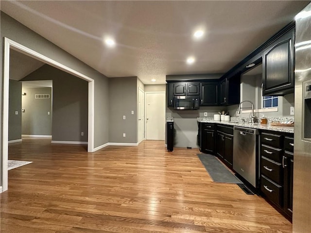 kitchen featuring sink, light hardwood / wood-style flooring, light stone countertops, and dishwasher