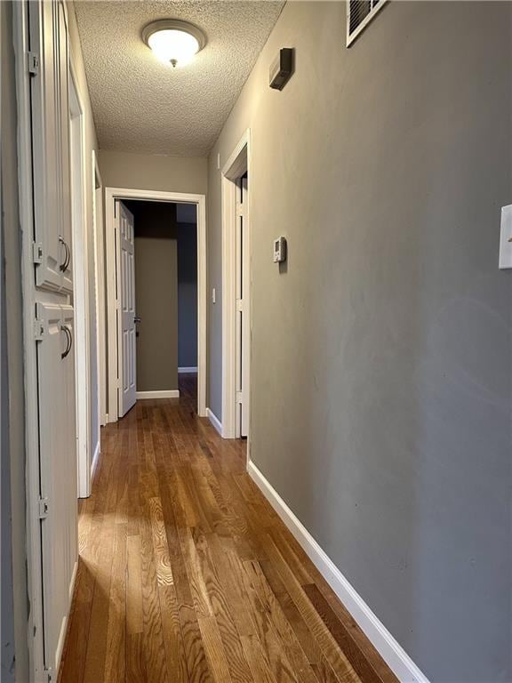 hall with wood-type flooring and a textured ceiling