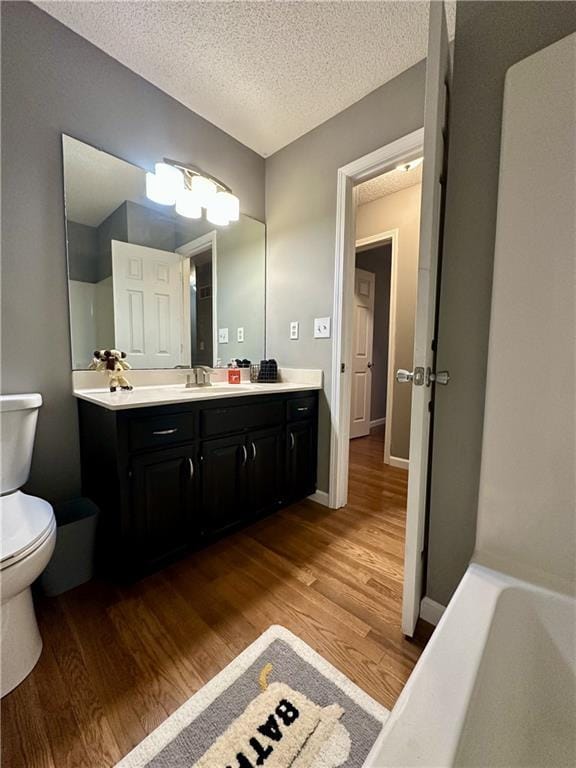 bathroom featuring vanity, hardwood / wood-style floors, a textured ceiling, and toilet