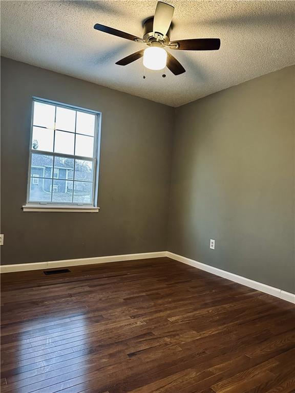 unfurnished room featuring ceiling fan, dark hardwood / wood-style floors, and a textured ceiling