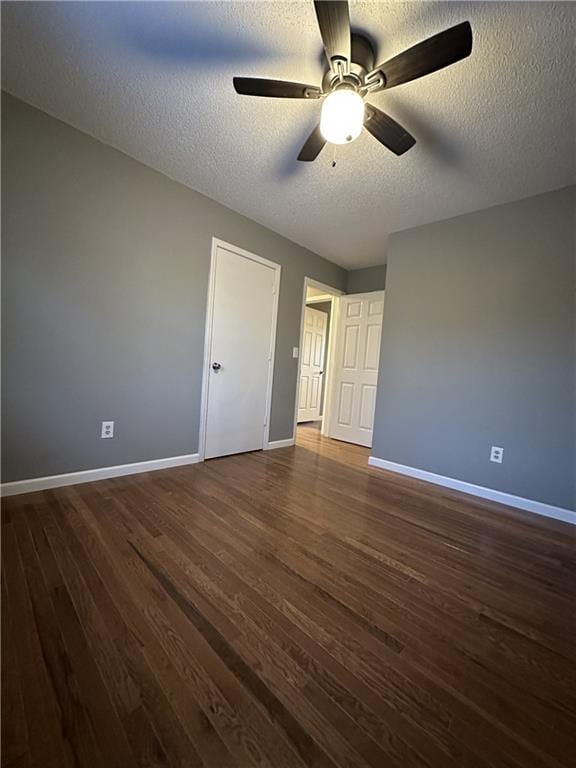 unfurnished bedroom with dark hardwood / wood-style flooring, ceiling fan, and a textured ceiling