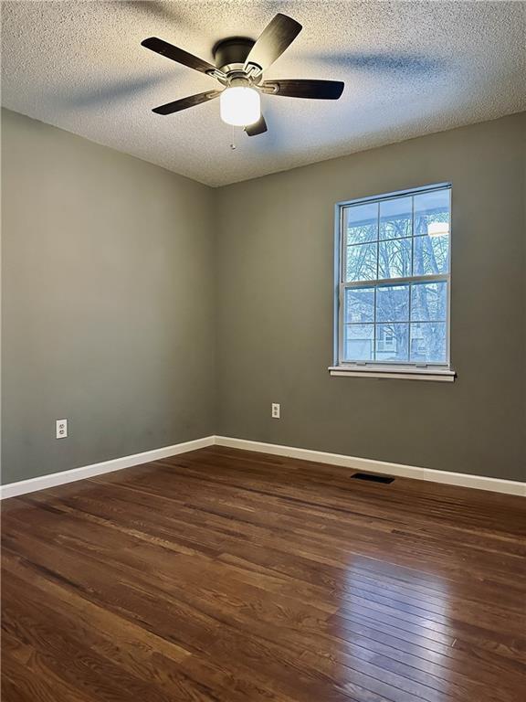 spare room featuring a textured ceiling, dark wood-type flooring, and ceiling fan