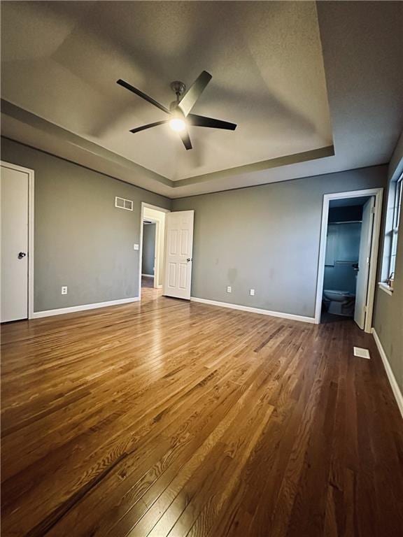 unfurnished bedroom featuring ceiling fan, wood-type flooring, and a tray ceiling