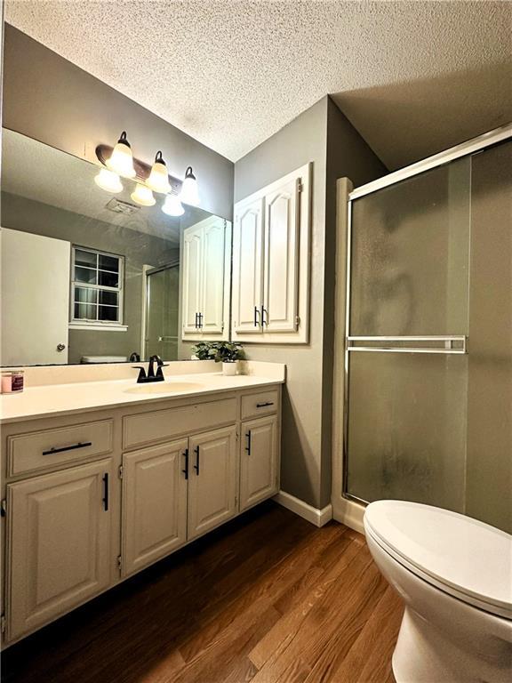 bathroom featuring walk in shower, vanity, hardwood / wood-style floors, and a textured ceiling