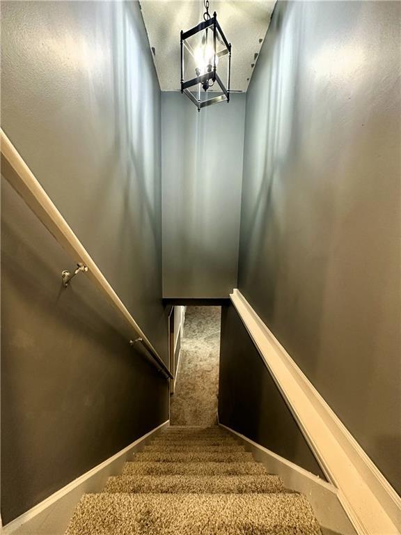 stairway featuring carpet flooring and a chandelier