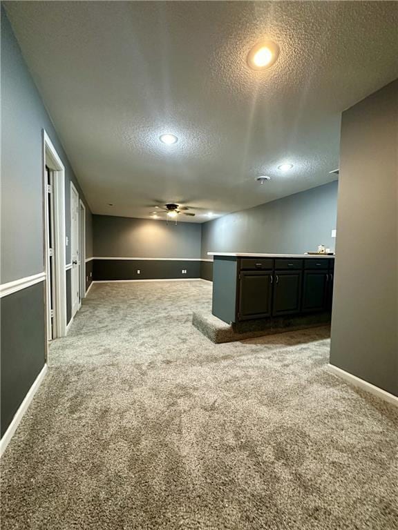 carpeted spare room featuring ceiling fan and a textured ceiling