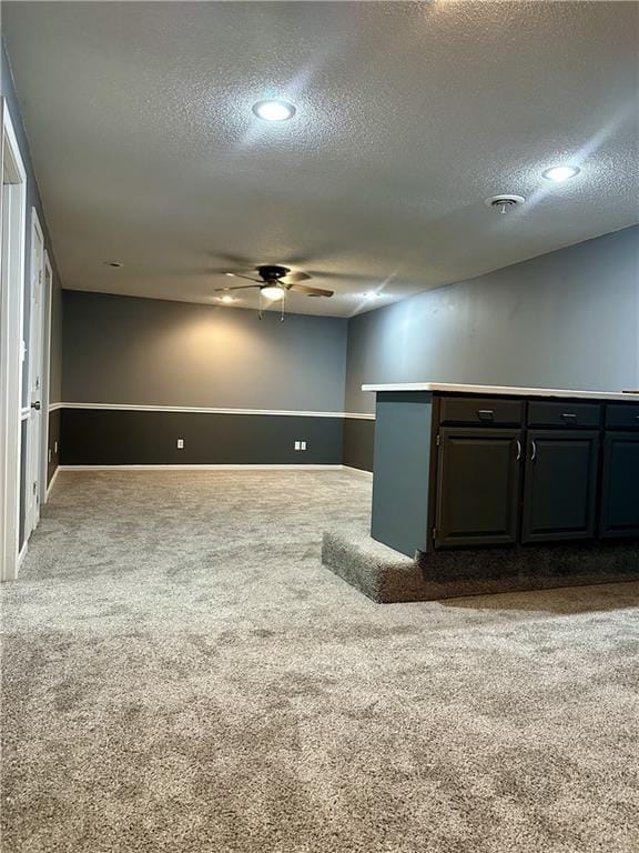 unfurnished room with a textured ceiling, ceiling fan, and carpet flooring