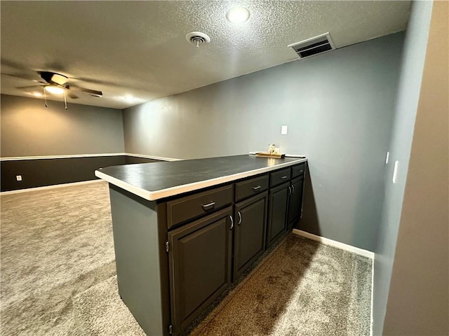 kitchen featuring dark brown cabinetry, a textured ceiling, kitchen peninsula, ceiling fan, and carpet