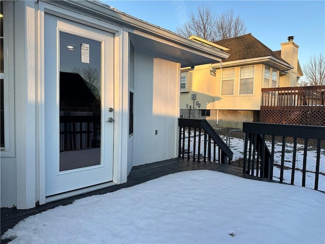 snow covered property entrance with a wooden deck