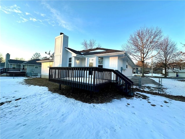 snow covered rear of property with a deck