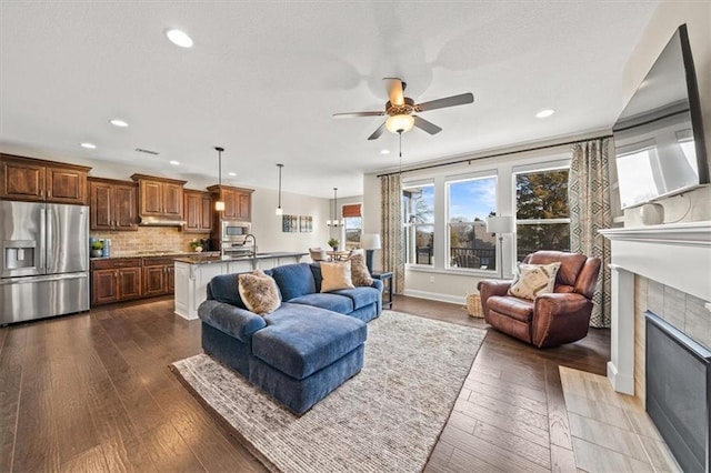 living room featuring ceiling fan, dark hardwood / wood-style flooring, sink, and a tile fireplace