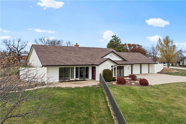 ranch-style home featuring a chimney, an attached garage, fence, driveway, and a front lawn