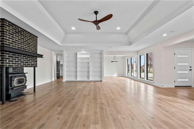 unfurnished living room with ceiling fan, recessed lighting, wood finished floors, a tray ceiling, and crown molding