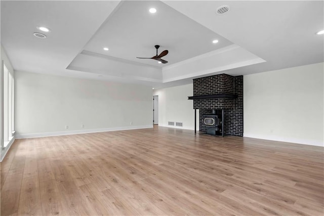 unfurnished living room with light wood-style flooring, a raised ceiling, and visible vents