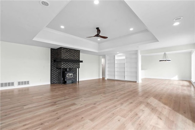 unfurnished living room with light wood-style floors, visible vents, and a tray ceiling