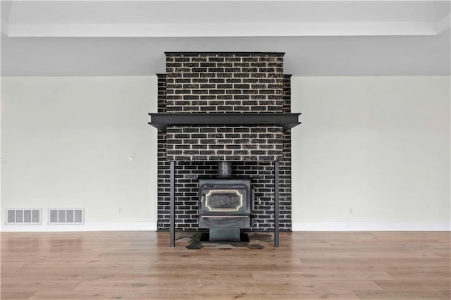 room details featuring a wood stove, visible vents, and wood finished floors