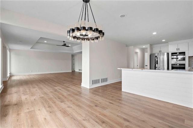 unfurnished living room featuring light wood-style floors, recessed lighting, visible vents, and a tray ceiling