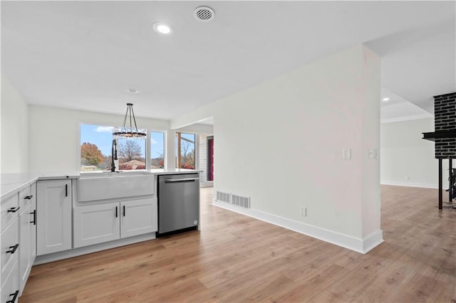 kitchen featuring light wood finished floors, visible vents, white cabinets, a sink, and dishwasher