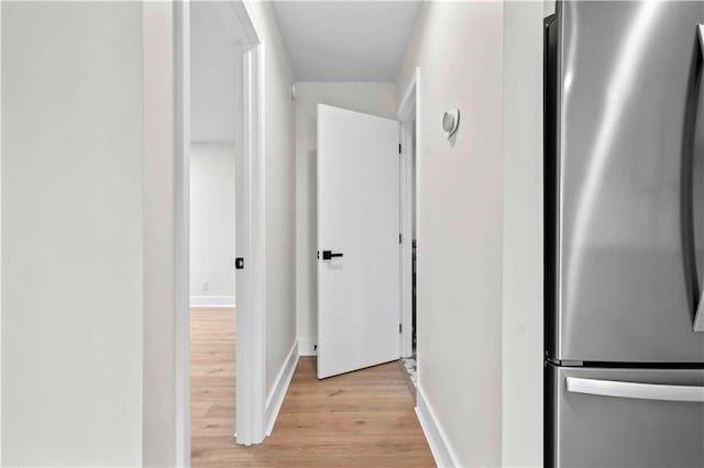 hallway featuring light wood-type flooring and baseboards