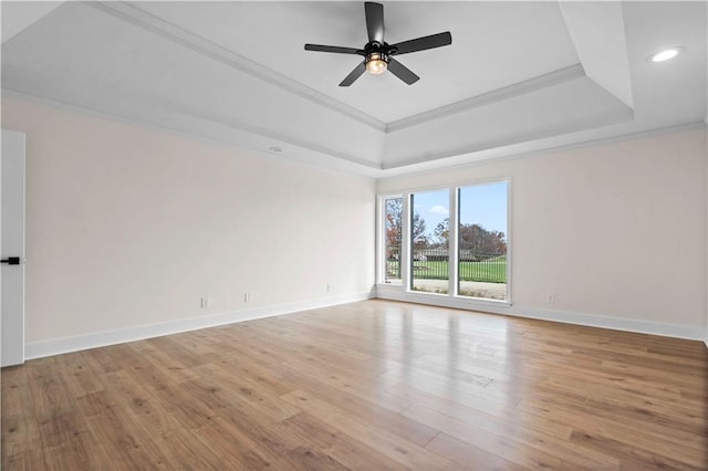 spare room featuring a tray ceiling, crown molding, and wood finished floors