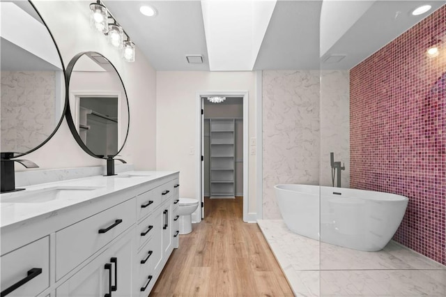 full bathroom featuring wood finished floors, a soaking tub, a sink, and double vanity