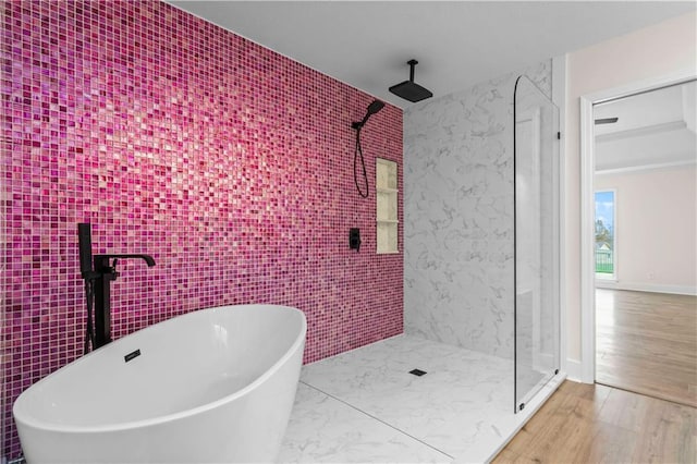 full bathroom with wood finished floors, a soaking tub, a tile shower, and tile walls