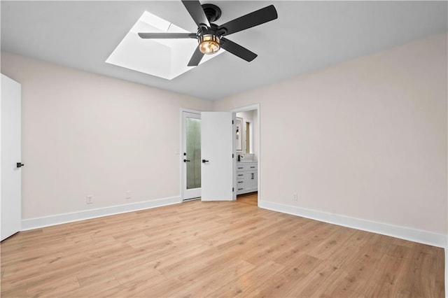 unfurnished bedroom featuring a skylight, baseboards, light wood finished floors, and a ceiling fan