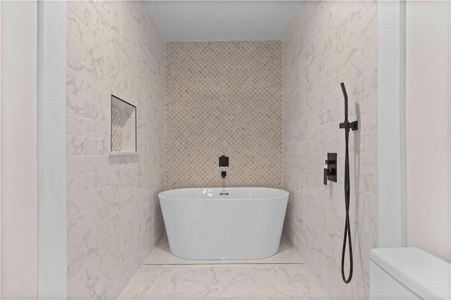 full bath featuring a freestanding bath, toilet, and tile walls